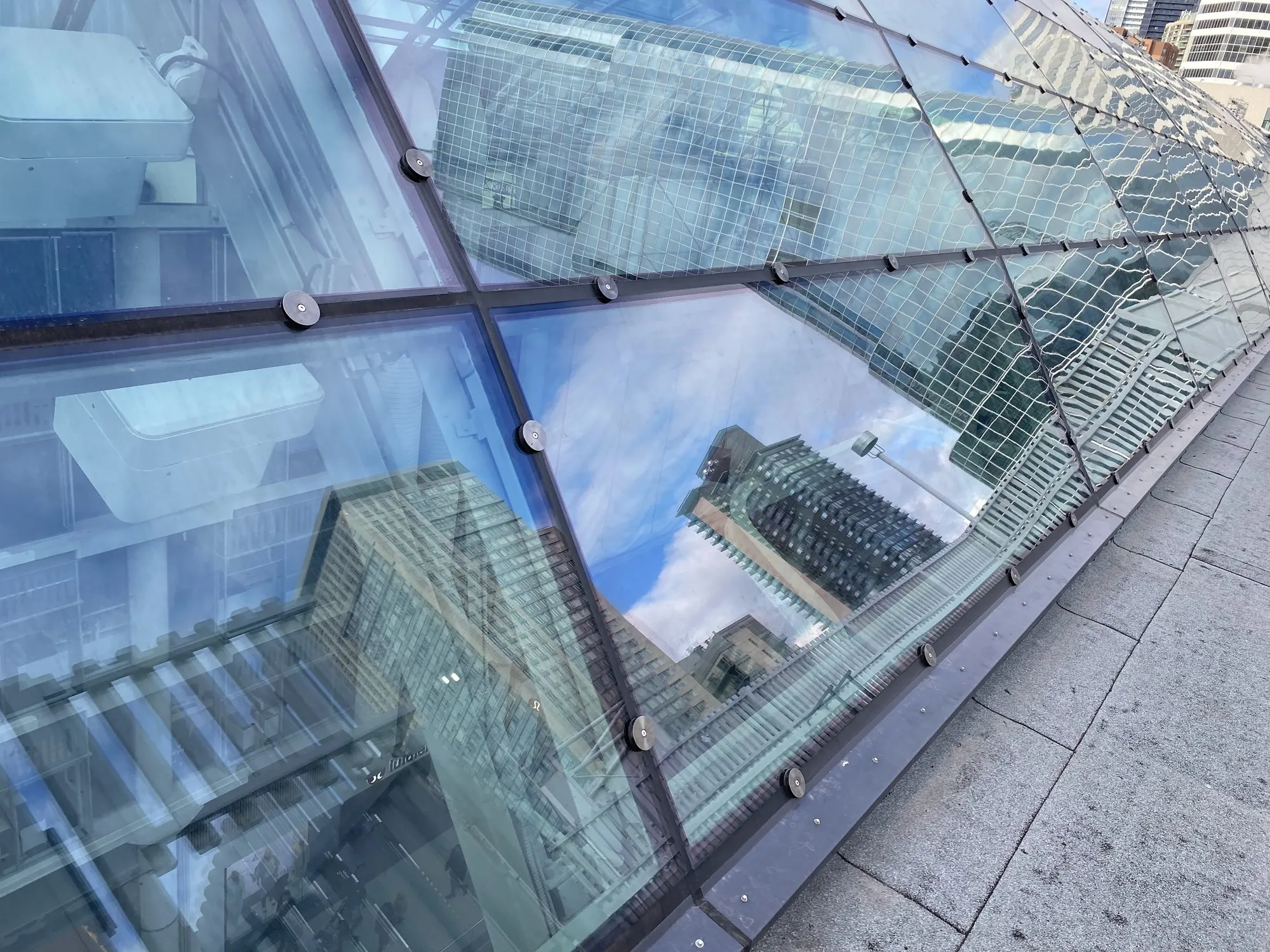 Completed skylight glazing on point fixings, reflecting the Toronto skyline and cloud